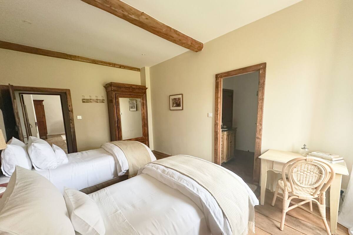 A room with two beds, a desk, a chair, and a mirror.
