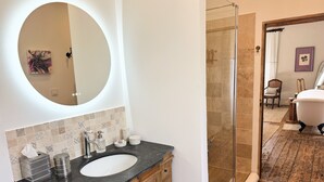 A bathroom with a round mirror, a sink, and a shower area. - Les Manibelles (Amarens)