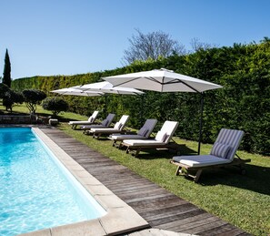 A poolside area with lounge chairs and umbrellas. - Les Manibelles (Amarens)