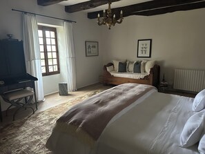 Ein Schlafzimmer mit einem Bett, einer Holzbank, einem Schreibtisch, einer Chandelier und einer Heizung.