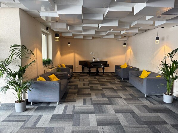 Un espace de détente moderne avec des canapés gris, un piano et des plantes en pot.