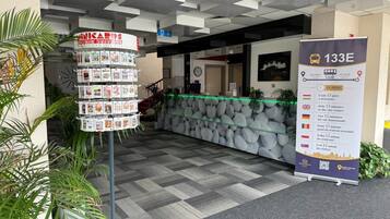 Zona de recepción de hotel con pared de piedra, un reloj y un cartel que indica la distancia al centro de la ciudad.