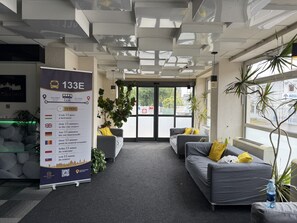 Un hall d’hôtel doté d’une grande affiche d’information, d’un espace salon et de grandes fenêtres.