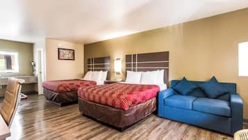 A hotel room with two beds, a blue sofa, a desk, and a window.