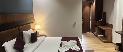 A hotel room with a bed, bedside lamp, and a wooden wardrobe.