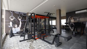 Une salle de sport équipée de divers appareils d’entraînement, notamment un support à squats, un banc de développé couché et des haltères.