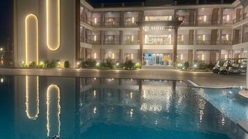 A hotel with a large pool, a modern building with vertical light strips, and a traditional multi-story structure with balconies.
