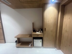 Een kamer met een houten bureau, een kleine koelkast en een kast.