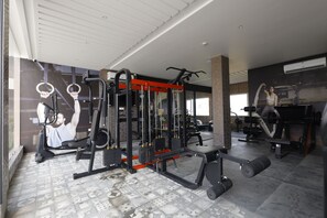 A gym with various exercise equipment, including a squat rack, bench press, and dumbbells. - Nirvana Grand Hotel And Resort (Gaya)