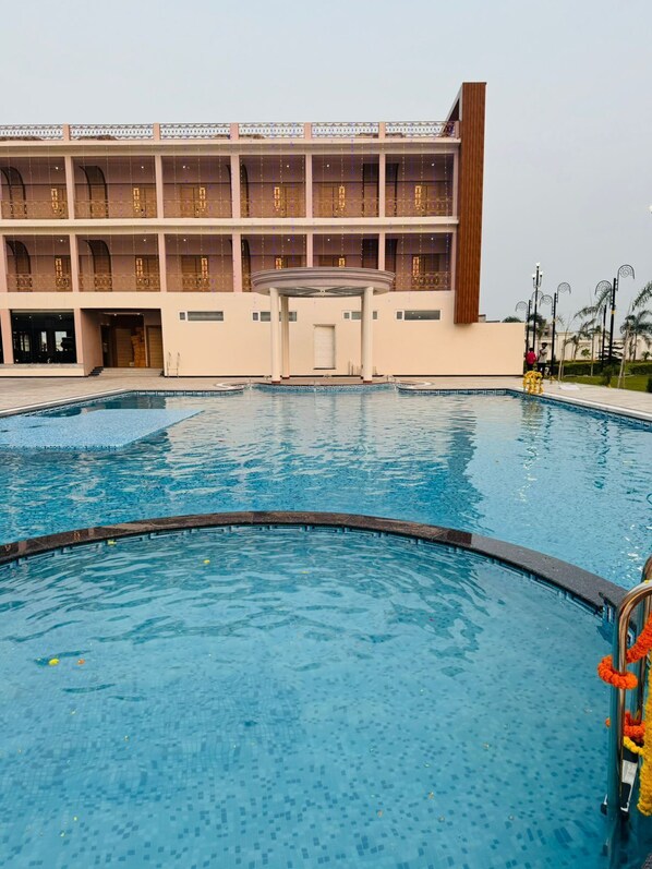 Un hôtel doté d’une grande piscine, d’un espace couvert et d’un bâtiment agrémenté de nombreux balcons.