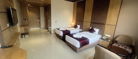 Habitación de hotel con dos camas, un escritorio, una silla y un televisor.