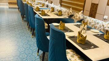 Un salón de conferencias con mesas largas, sillas azules y baldosas de suelo estampadas.