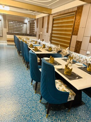 Une salle de conférence avec de longues tables, des chaises bleues et des carreaux de sol à motifs.