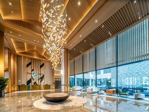 A modern lobby with a central seating area, a decorative hanging installation, and large windows offering views. - Holiday Inn Ningde Jiaocheng (Ningde)