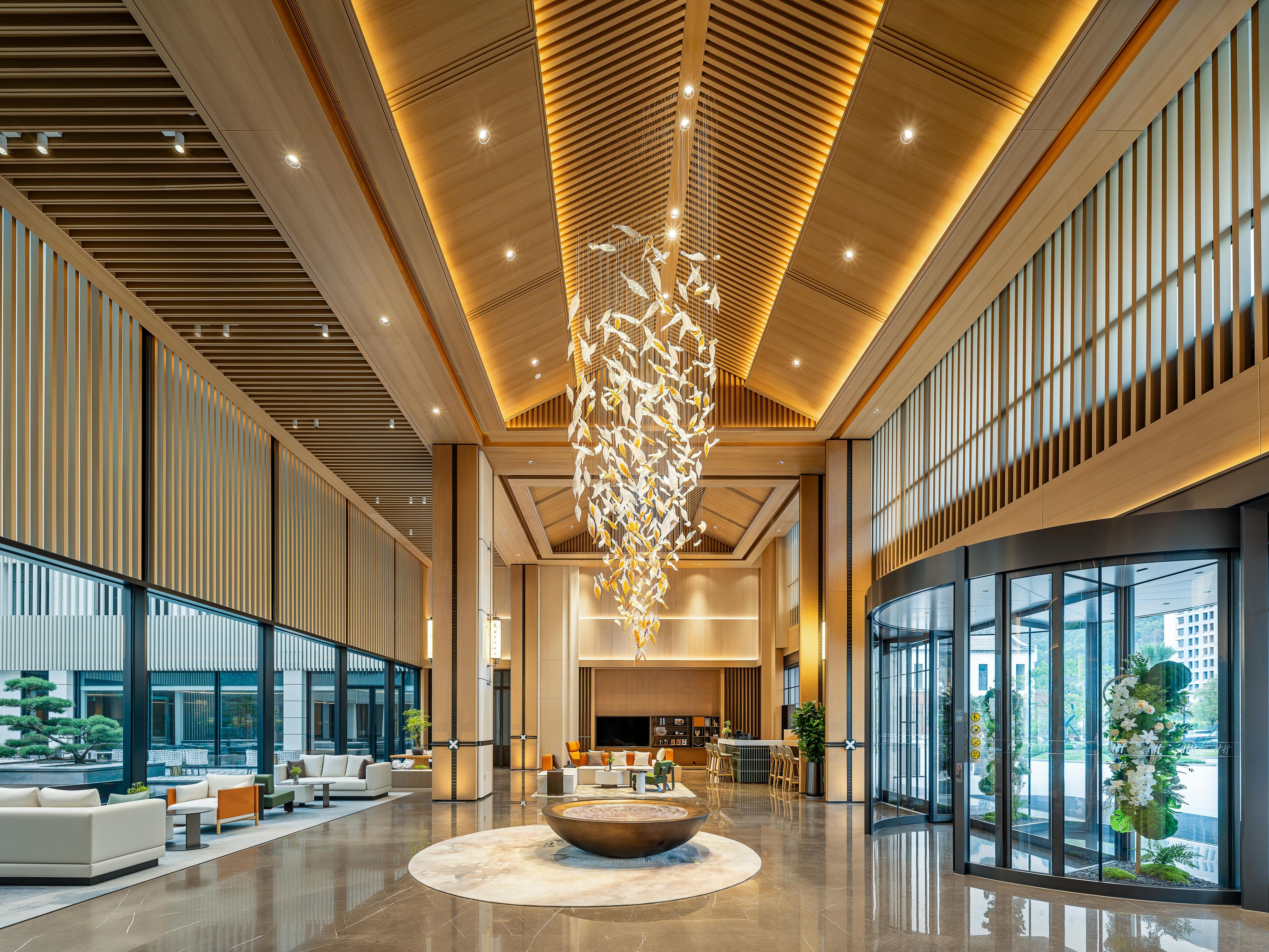 A spacious lobby with a central seating area, large windows, and a modern ceiling design.