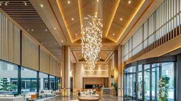 A spacious lobby with a central seating area, large windows, and a modern ceiling design.
