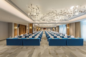 A conference room with rows of tables, chairs, and a modern chandelier. - Holiday Inn Ningde Jiaocheng (Ningde)