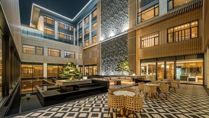 Ein moderner Innenhof eines Hotels mit einer zentralen Sitzgruppe, einem Wasserspiel und einem gemusterten Boden.