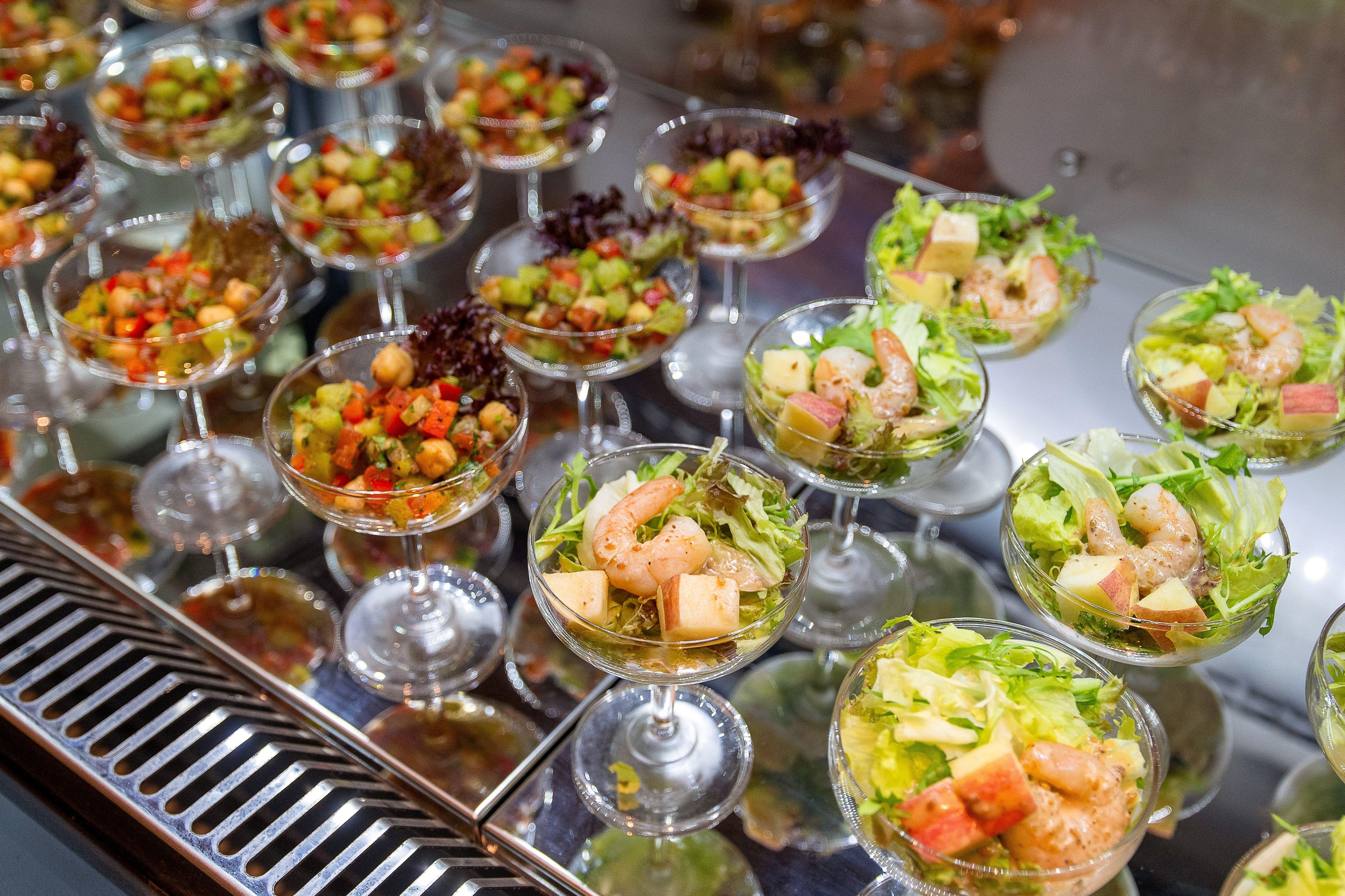 A buffet with various dishes in clear glass bowls.