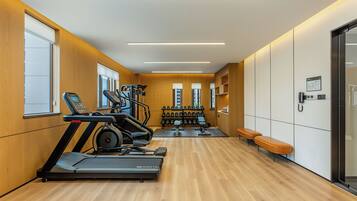 A modern gym with treadmills, dumbbells, and benches.