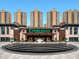 Un hotel con fachada moderna, entrada principal y una fuente en el frente.