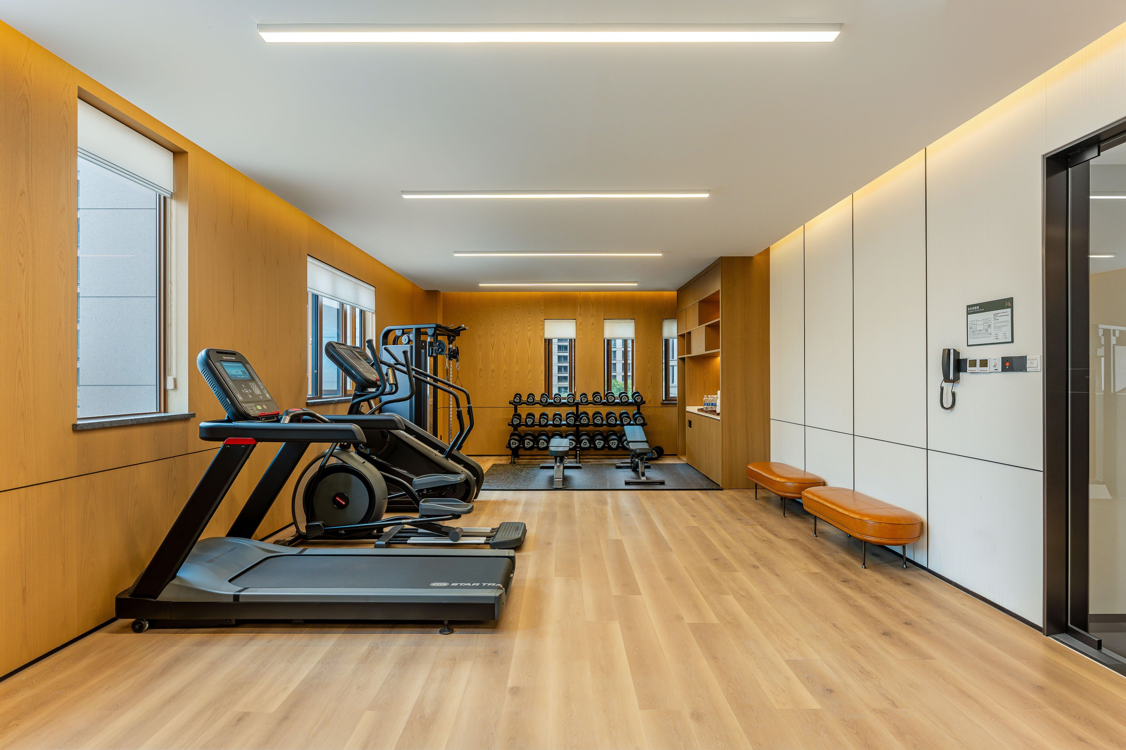 Un gimnasio con cintas de correr, mancuernas y bancos.