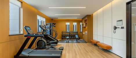 Un gimnasio con cintas de correr, mancuernas y bancos.