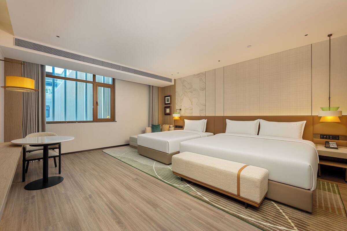 Ein Hotelzimmer mit einem großen Bett, zwei Nachttischen, einem kleinen Tisch und einem Sessel.