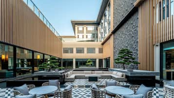 A courtyard with outdoor seating, a central sofa, and a geometric tiled floor.