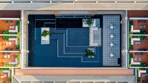 Vista aérea de una terraza en la azotea con arreglos geométricos de asientos, una fuente central y vegetación circundante.