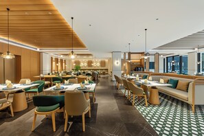 A spacious dining area with multiple tables and chairs, a central seating area with a sofa, and a checkered floor pattern.