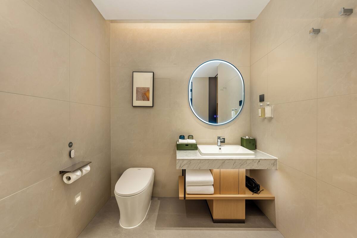 Ein modernes Badezimmer mit Toilette, Waschbecken und Spiegel.