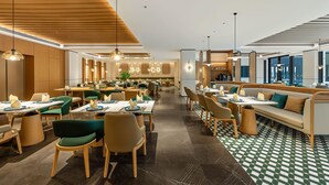 A modern hotel dining area with wooden ceiling panels, green and beige chairs, and a checkered floor pattern. - Holiday Inn Ningde Jiaocheng (Ningde)
