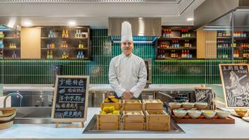 Un chef se tient derrière un comptoir, devant lequel sont disposés divers aliments et condiments.