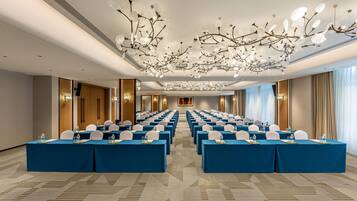 A conference room with rows of tables, chairs, and a modern chandelier.