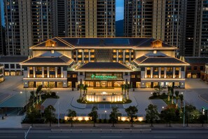 Un hotel de varios pisos con un patio central, ventanas amplias y una entrada destacada.
