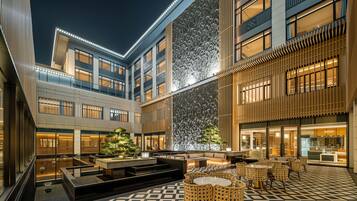 A modern hotel courtyard with a central seating area, a water feature, and a patterned floor.