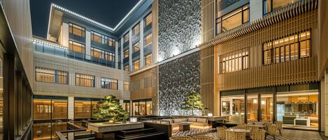 Un patio moderno de hotel con una zona de estar central, una fuente de agua y un suelo con diseño.