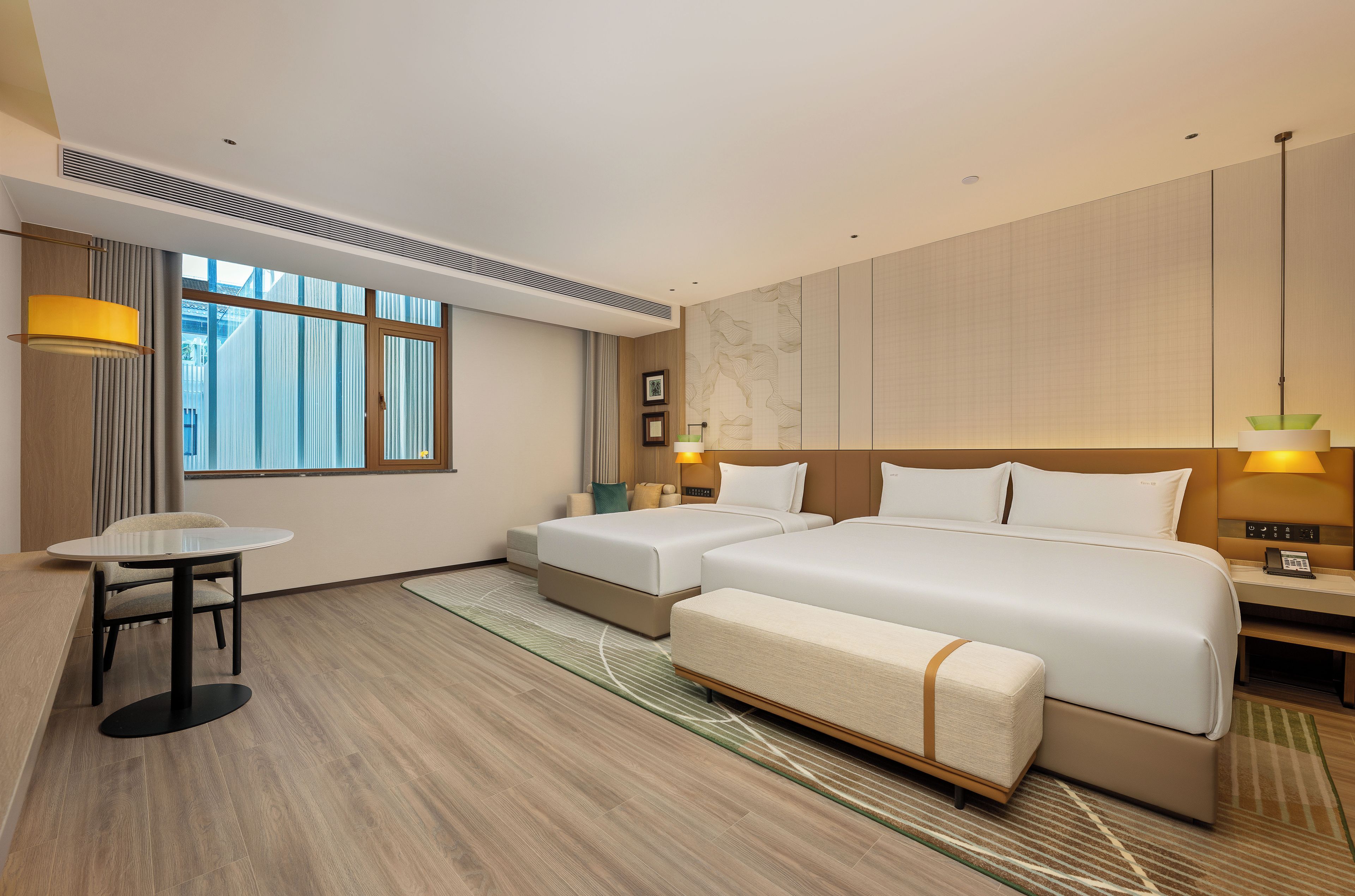 A hotel room with a large bed, two bedside tables, a small table, and a chair.