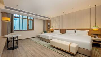 A hotel room with a large bed, two bedside tables, a small table, and a chair.