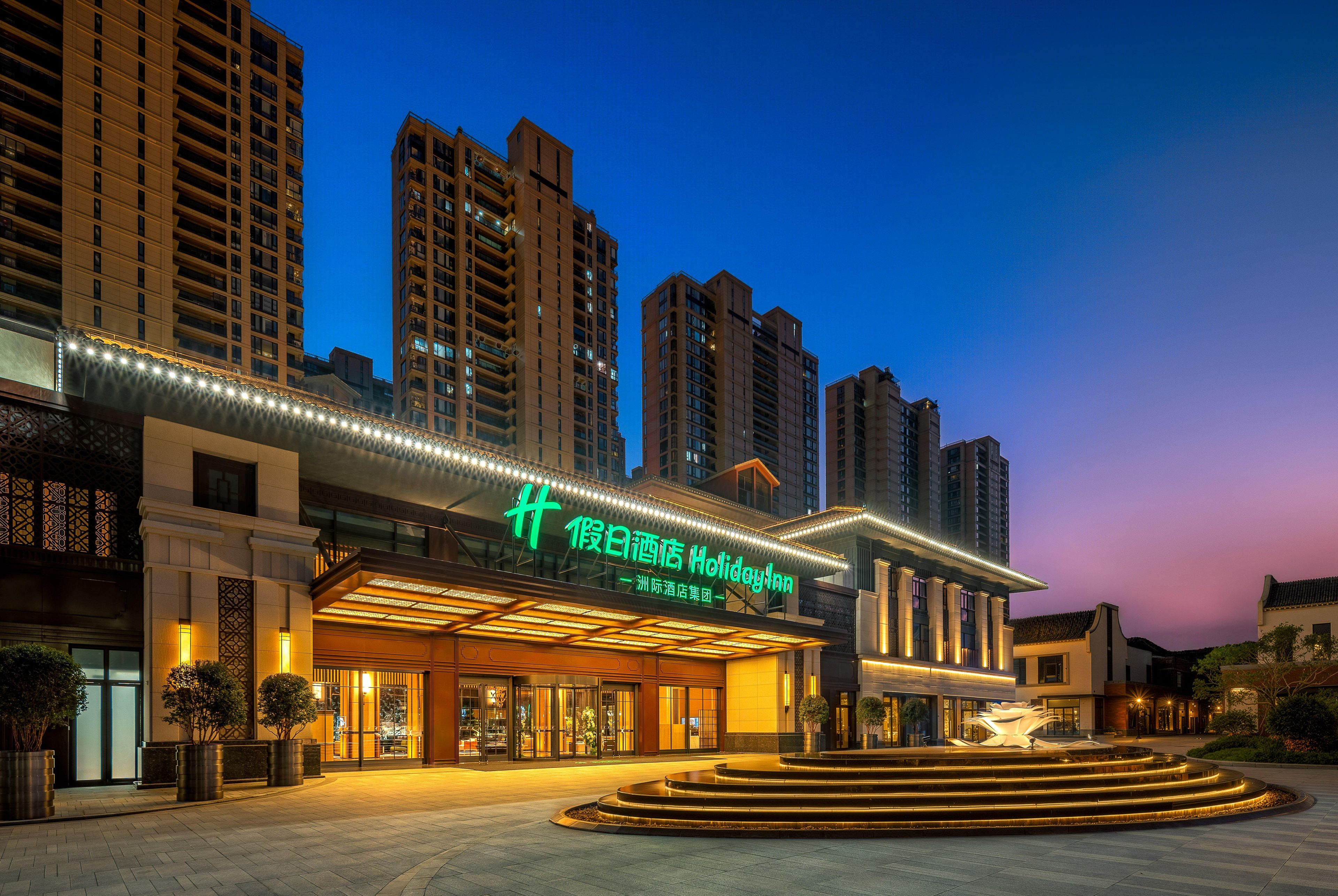 Un hotel con fachada moderna, entrada destacada y zona exterior bien iluminada.