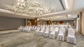 A conference room with rows of white chairs, a patterned carpet, and a modern chandelier.