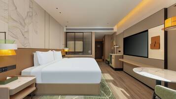 Una habitación de hotel moderna con una cama grande, mesitas de noche, un escritorio, una silla, un televisor y una pequeña mesa.