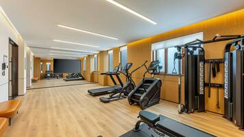 A gym with cardio machines, weightlifting equipment, and benches.