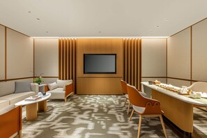 A modern hotel room with a flat-screen TV, a sofa, a dining table, and a patterned carpet. - Holiday Inn Ningde Jiaocheng (Ningde)
