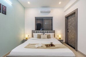 A neatly made bed with a tray of drinks and a book, bedside lamps, and a window with a view. - Alaya Stays By Elivaas Lake City Heights (Udaipur)