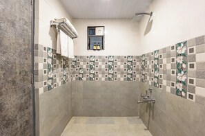 Une salle de bain avec une douche, un porte-serviettes et une petite fenêtre ornée de bouteilles.