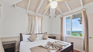 Een slaapkamer met een houten bed, een plafondventilator, een raam met uitzicht en een deur.