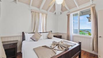 A bedroom with a wooden bed, a ceiling fan, a window with a view, and a door.