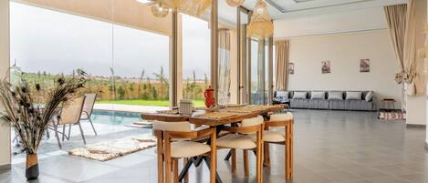 A spacious living area with a large dining table, comfortable seating, and a view of the outdoors.